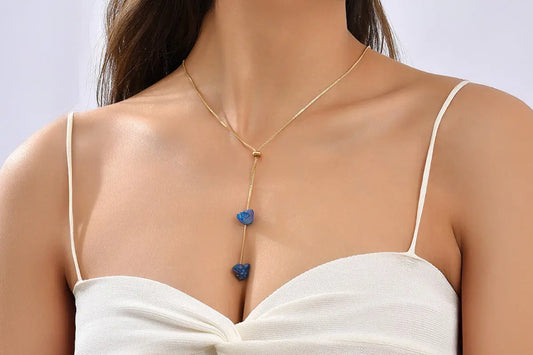 Minimalist jewelry including simple gold chains, rings and earrings styled on white fabric