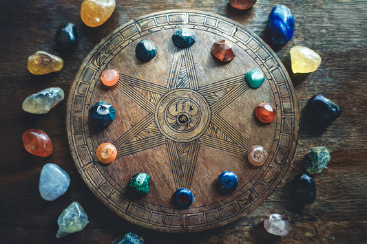 Zodiac birthstones arranged around a wooden zodiac wheel in natural light.