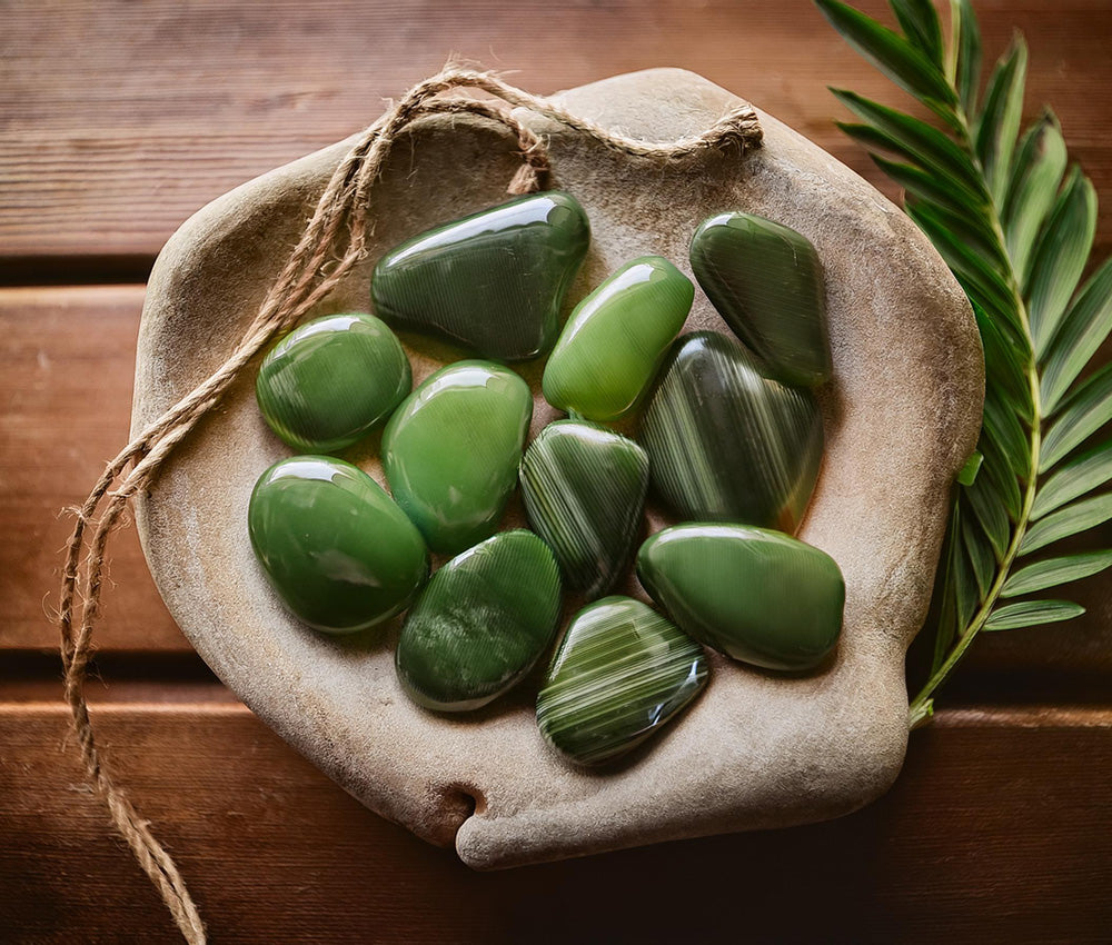 Polished green aventurine stones on a textured surface, symbolizing good fortune, courage, and spiritual insight.