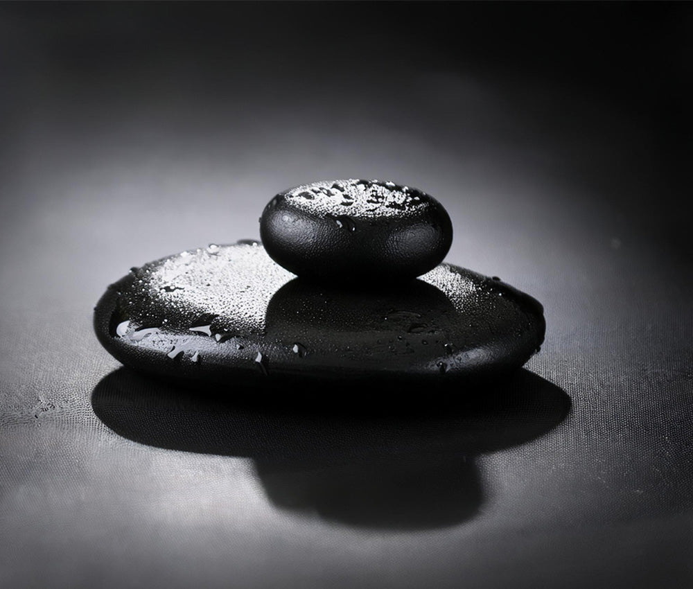 Black obsidian stones on a neutral surface, emphasizing their connection to the Root Chakra and grounding energy.