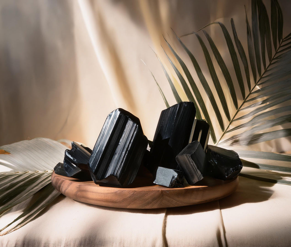 Black tourmaline stones placed on a neutral background, highlighting their grounding energy and connection to the Root Chakra.