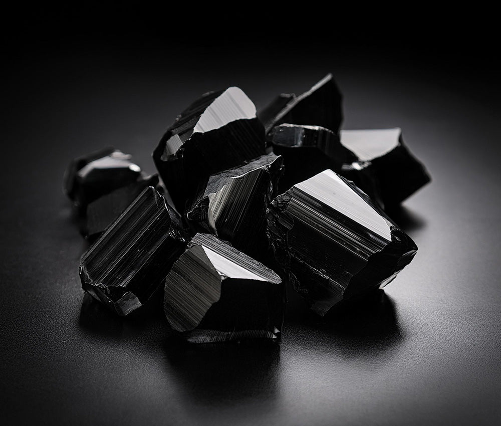 Black tourmaline stones with a textured background, symbolizing protection and grounding with natural elements.