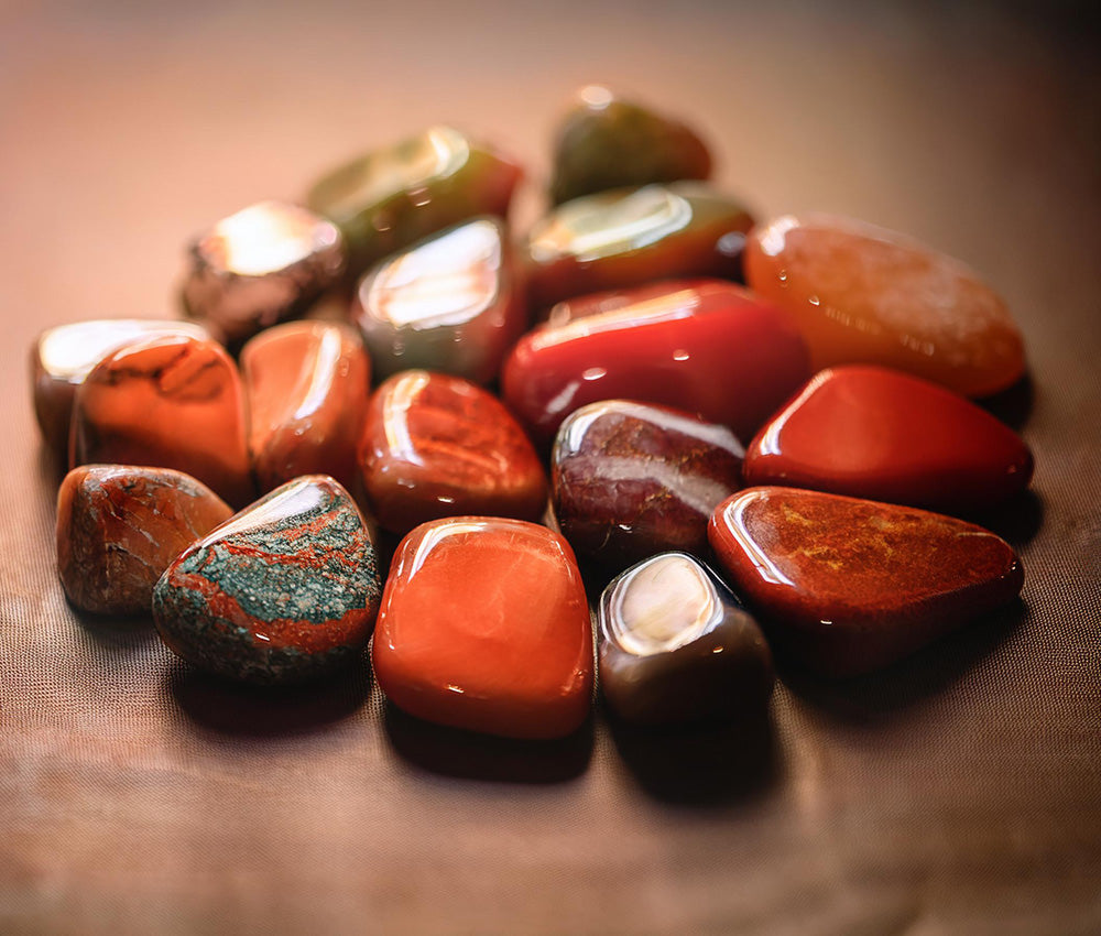 Jasper stones arranged by color on a plain surface, emphasizing their connection to grounding, creativity, and emotional harmony.