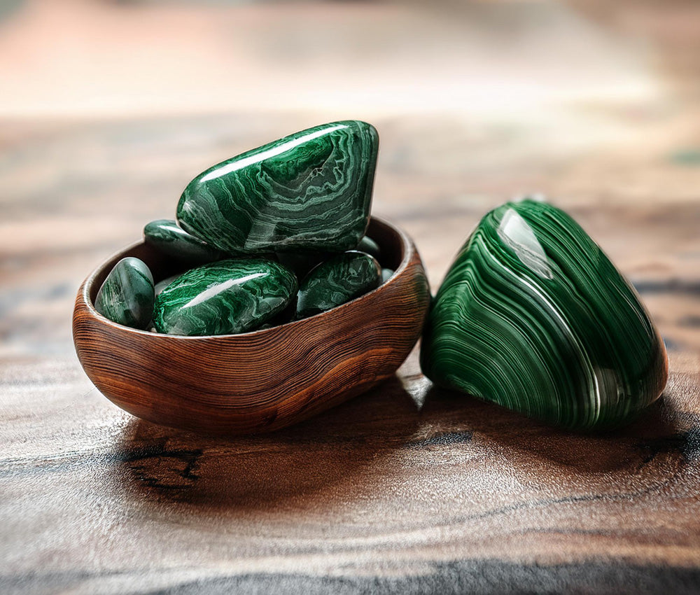 Malachite stones on a neutral background with soft lighting, symbolizing protection, prosperity, and their historical use in ancient cultures.