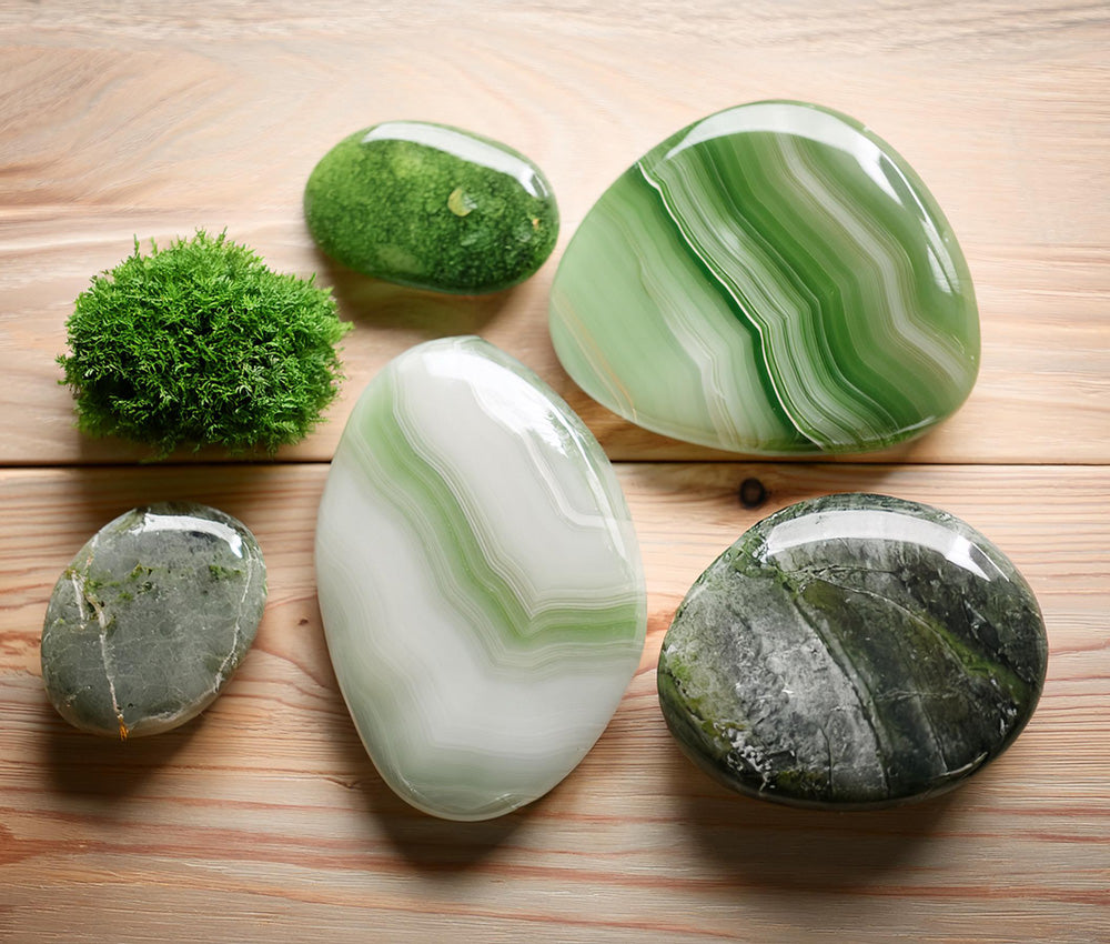 Moss agate stones on a textured surface with greenery, symbolizing nature’s beauty, abundance, and historical significance in agriculture.