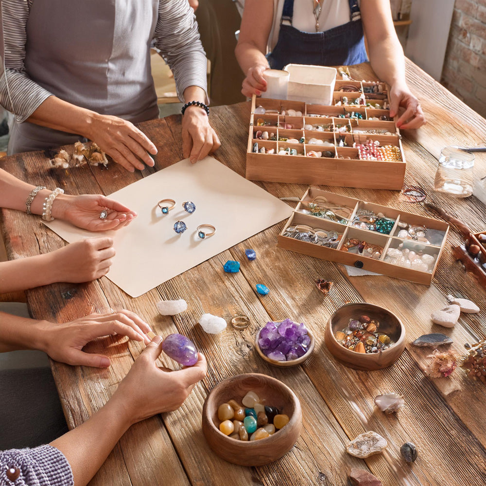 Passionate creators gathered around a wooden table, selecting gemstones and discussing holistic product ideas.