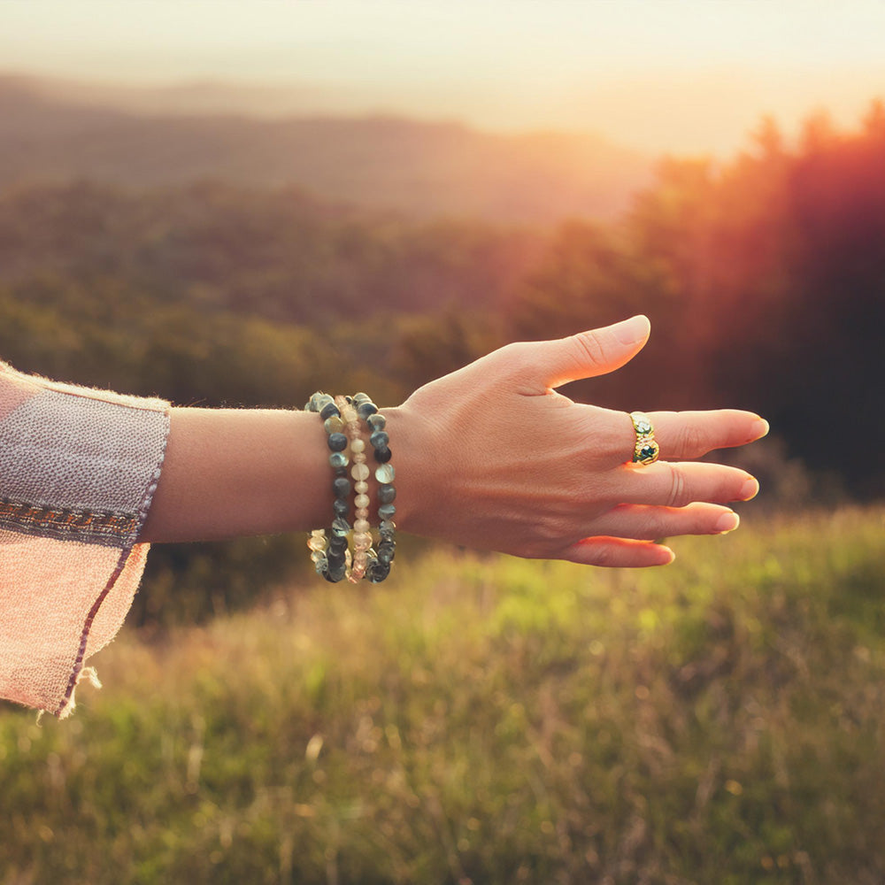 A warm outdoor scene of a person wearing a gemstone bracelet, inviting the viewer to join a journey toward balance.