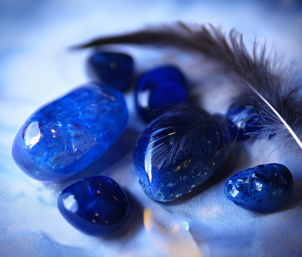 Sapphire stones on a light surface, highlighting their connection to the Third Eye and Throat Chakras for intuition and truthful communication.