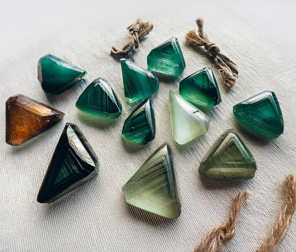 Tourmaline stones in vibrant colors on a neutral surface, symbolizing protection, transformation, and their historical significance.